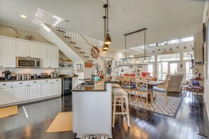 A spacious kitchen with white cabinets, a central island, and a dining area with wooden chairs and a patterned rug. - Marina & Golf Course Views: Edisto Island Home (Edisto Island)
