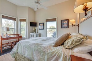 A bedroom with a bed, a desk, a chair, a ceiling fan, and a TV. - Marina & Golf Course Views: Edisto Island Home (Edisto Island)