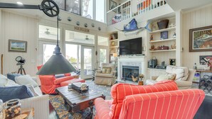 A spacious living room with a high ceiling, a fireplace, and a balcony with a view. - Marina & Golf Course Views: Edisto Island Home (Edisto Island)