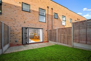 A modern brick building with a sliding glass door leading to a dining area. - Stylish 4 Bedroom Townhouse - Garden - Balconies - Parking (Birmingham)
