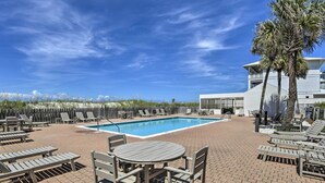 Ein Poolbereich mit Liegestühlen, einem Tisch und Blick aufs Meer.