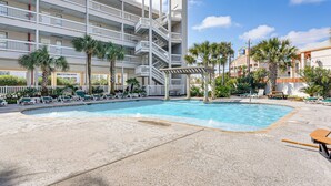 A hotel with a pool, multiple balconies, and palm trees. - Walk to Galveston Beach: Resort-Style Gem w/ Pool (Galveston)