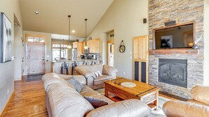 A spacious living room with leather sofas, a wooden coffee table, and a stone fireplace.