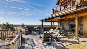 A patio with outdoor furniture, a stone fireplace, and a view of the mountains.