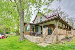 A log cabin with a porch, outdoor seating, and a staircase leading to the entrance. - Lakefront Getaway w/ Fire Pit in Akron (Akron)