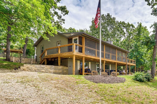 A two-story house with a covered porch and a flagpole. - Truman Lake Retreat: Relax and Unwind (Clinton)