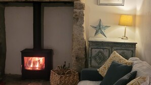 A cozy room with a stone fireplace, a bed with pillows, a bedside table with a lamp, and a framed picture on the wall.