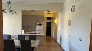 Eine moderne Küche mit einer zentralen Kochinsel, einem Essbereich mit Stühlen und einem Flur mit einer Wanduhr.