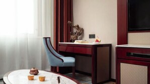 Habitación de hotel con escritorio, silla y una pequeña mesa con tazas y una tetera.