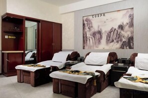 A room with massage therapy beds, a wardrobe, and a large painting on the wall.
