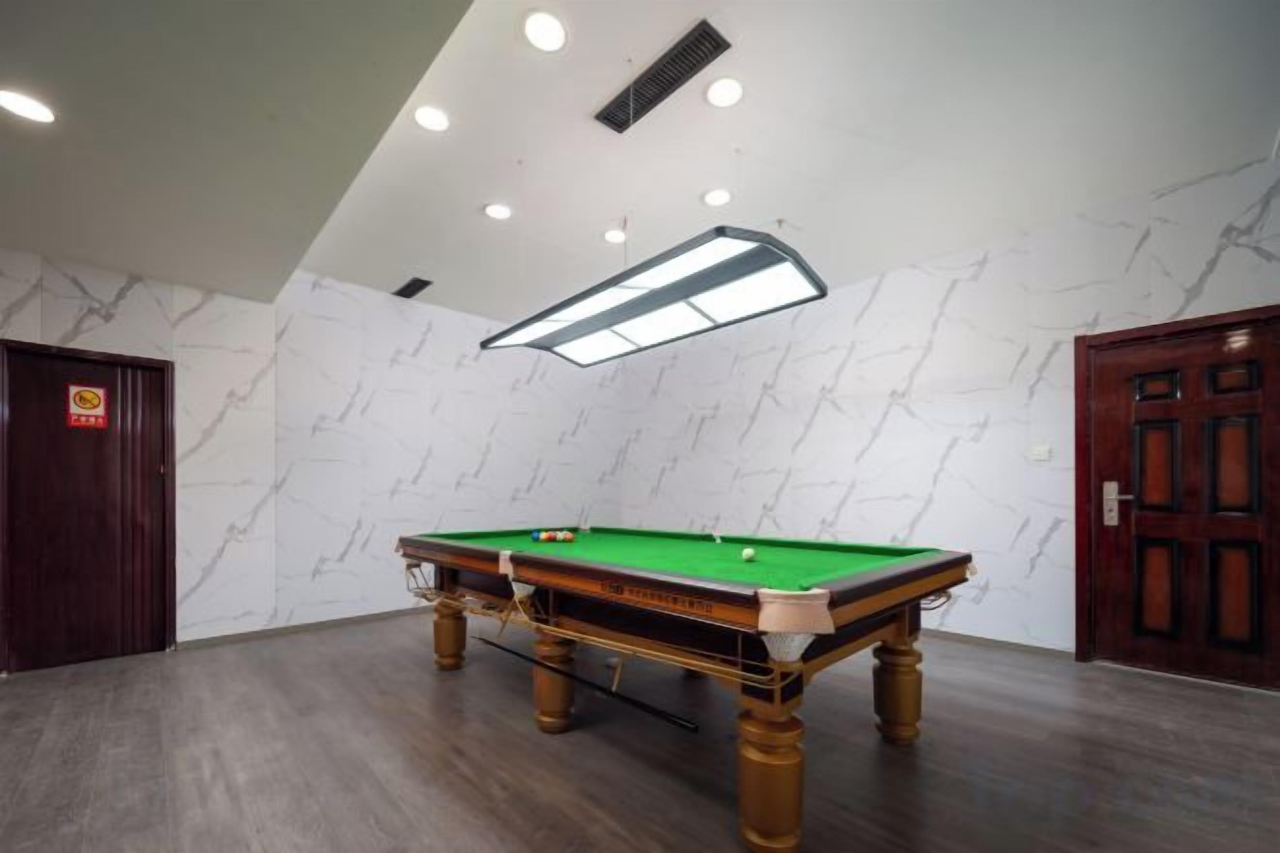 A billiards table in a room with a marble-patterned wall and a wooden door.