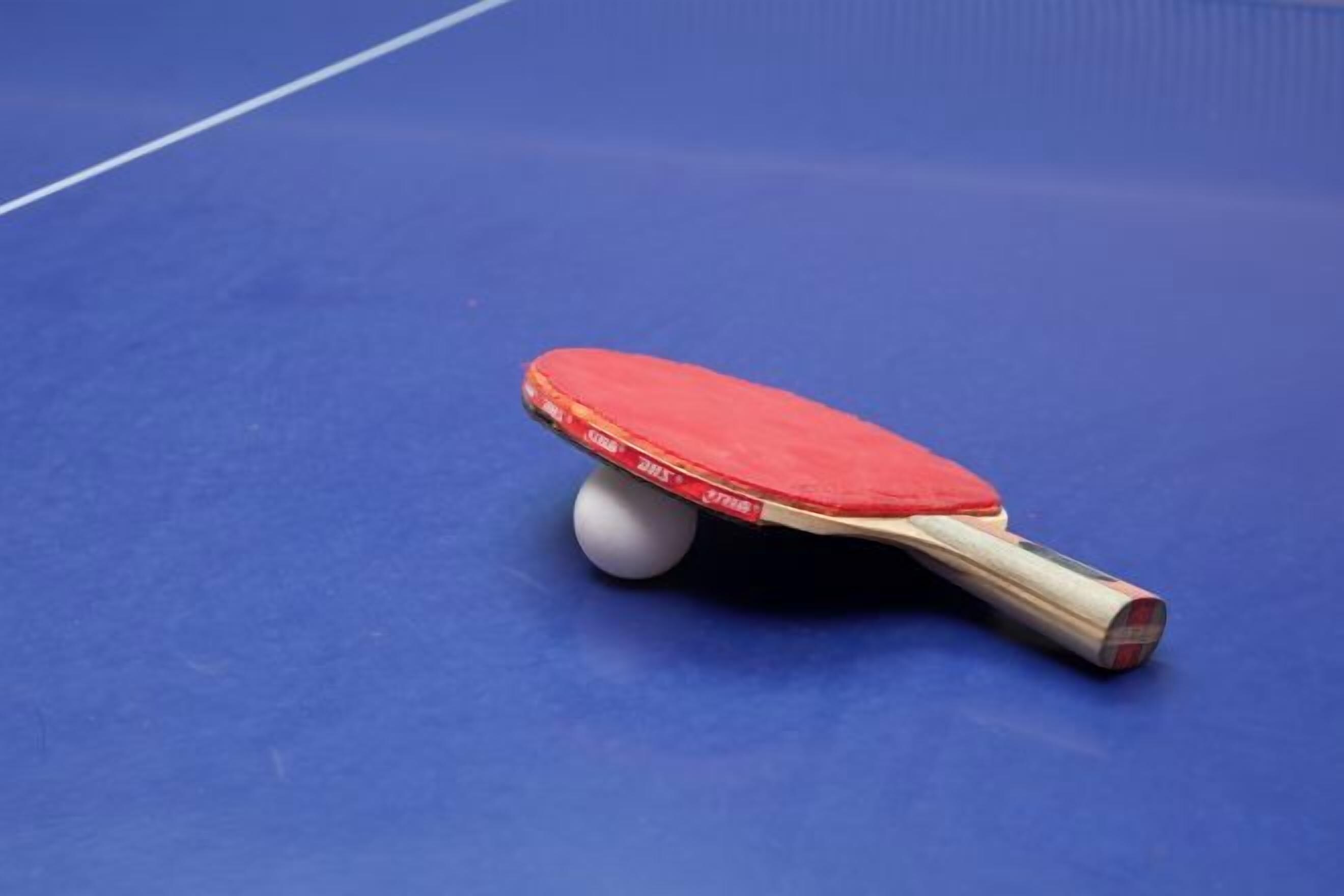 A table tennis paddle on a blue table.