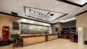 Zona de recepción de un hotel con mostrador de mármol, un acuario y una pared decorativa.