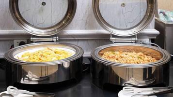 Two stainless steel food dispensers with lids open, containing what appears to be scrambled eggs and noodles.