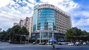 Un hotel de varios pisos con fachada curva, amplias ventanas y un letrero que indica que se trata de un hotel.