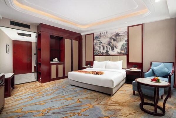 Une chambre d’hôtel avec un lit, un bureau, une chaise, une petite table et un tableau au mur.