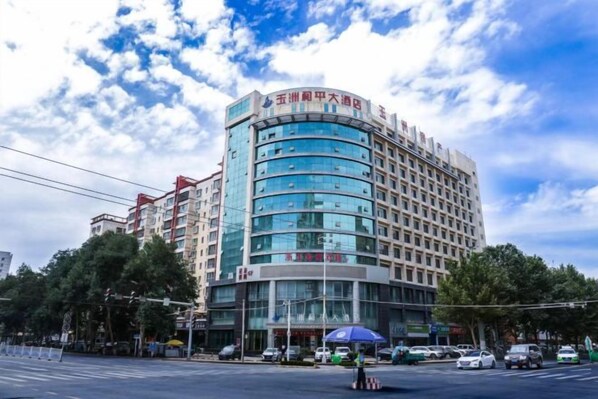 A multi-story hotel with a curved facade, large windows, and a prominent entrance with a blue awning.