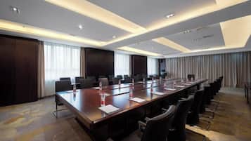 A conference room with a long table, multiple chairs, and a projector screen.