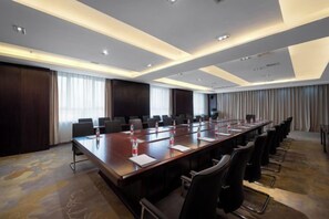 A conference room with a long table, multiple chairs, and a projector screen.