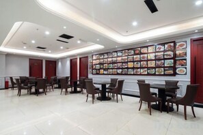 Un espace repas doté de plusieurs tables et chaises, d’un mur orné de photos de plats et d’un design de plafond moderne.