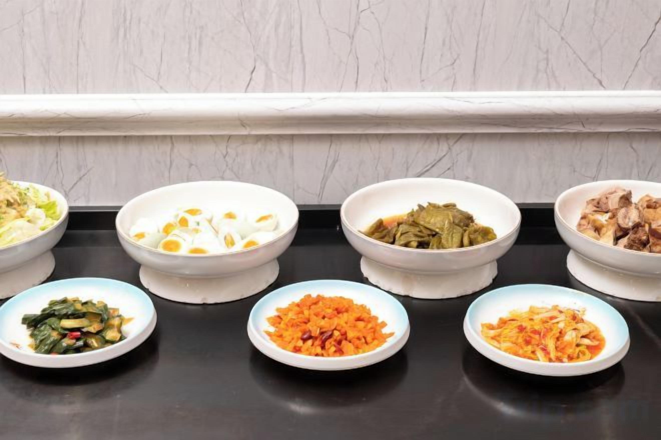 A row of bowls with various dishes on a black countertop.