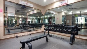 Un gimnasio con paredes espejadas, bancos de pesas y mancuernas.