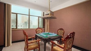 Una habitación con una mesa y cuatro sillas, una ventana con cortinas y una lámpara colgante.