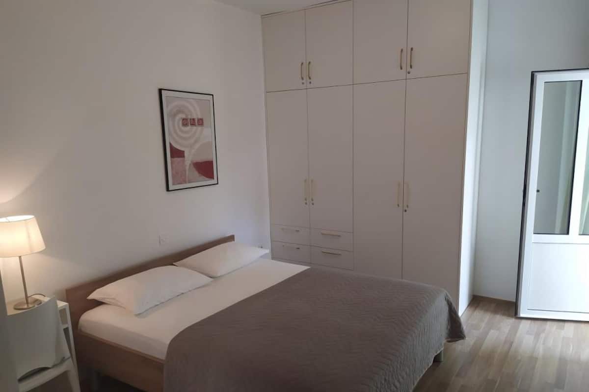 Une chambre à coucher avec un lit, une table de chevet, une armoire et une porte.