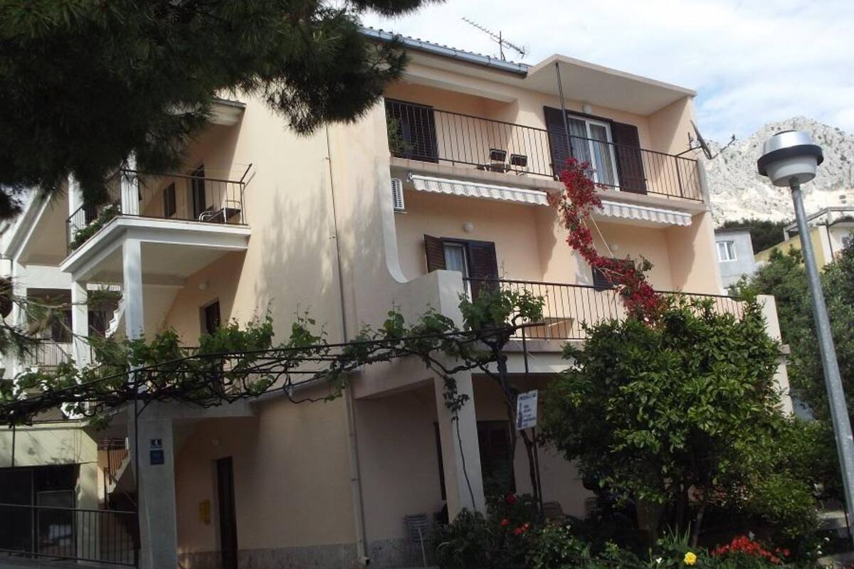 Un immeuble à deux étages doté de balcons, d’une entrée sécurisée par un portail et d’un panneau indiquant un espace de stationnement.