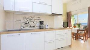 A modern kitchen with white cabinets, a coffee maker, and a wall art saying "I love coffee". - Apartments Roščić (Podgora)