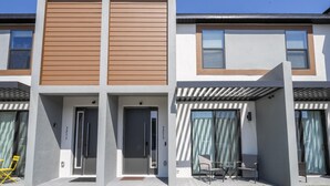Un bâtiment moderne à deux étages, doté d’un toit plat, de grandes fenêtres et d’un espace extérieur abrité avec des chaises, aménagé pour accueillir des personnes assises.