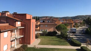 A residential area with terracotta-roofed buildings, a paved walkway, and parked cars. - Marina Portorož Family Friendly Apartment 1 (Piran)