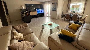 A modern living room with a sofa set, a coffee table, and a TV in the background. - Marina Portorož Family Friendly Apartment 1 (Piran)