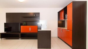 Een moderne keuken met donkere kastjes en een rode accentmuur.