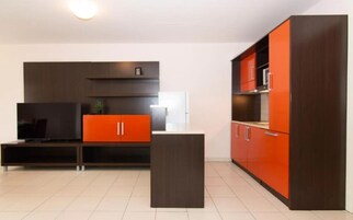 Una cocina moderna con armarios oscuros y una pared de acento roja.