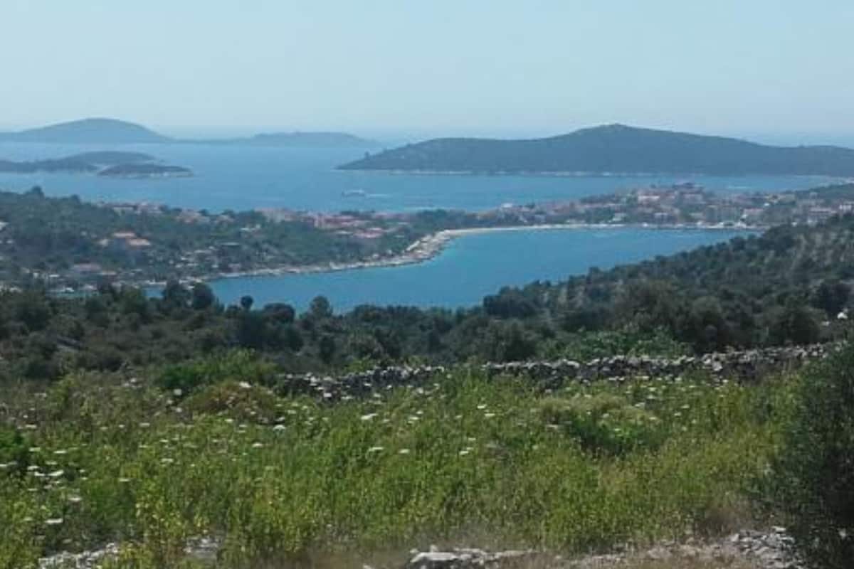 A coastal landscape with a view of a bay, hills, and a small town.