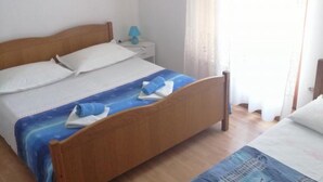Ein Einzelbett mit Holz Kopfteil, ein Nachttisch mit Lampe und ein Fenster mit Vorhängen.