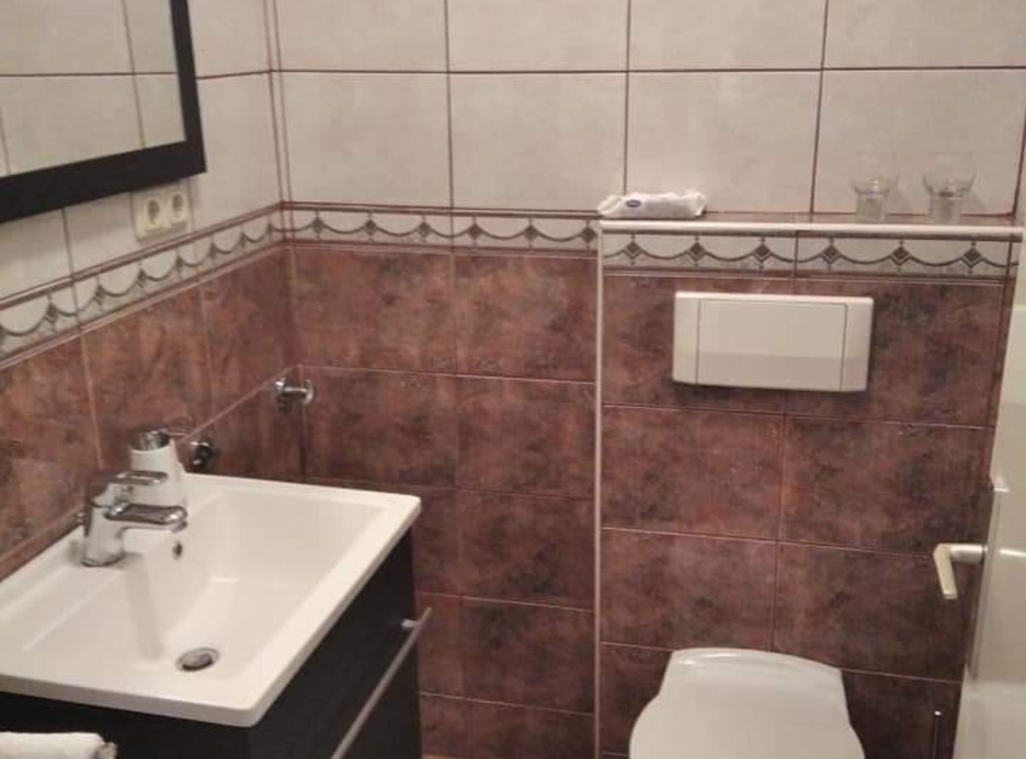 Un baño con lavamanos, espejo e inodoro.