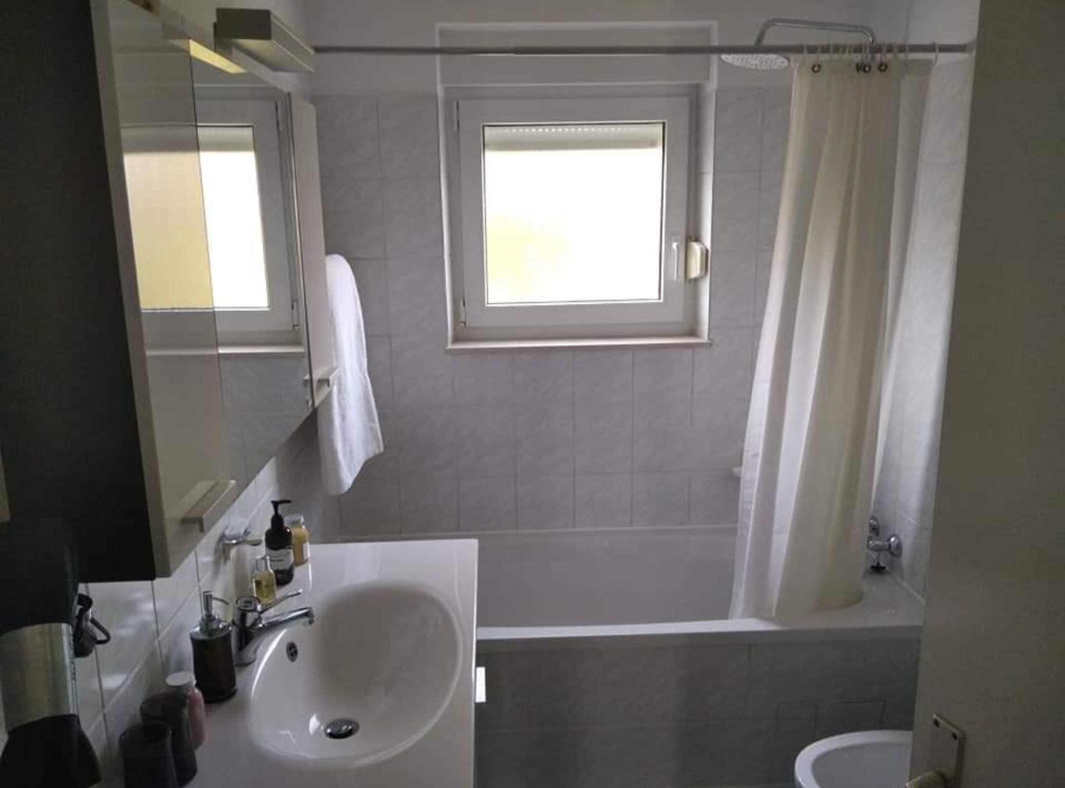 Ein Badezimmer mit Badewanne, Waschbecken, Spiegel und Fenster.