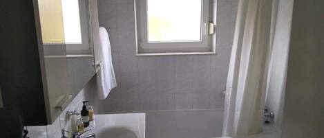 Ein Badezimmer mit Badewanne, Waschbecken, Spiegel und Fenster.