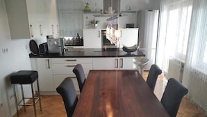 A modern kitchen with white cabinets, a wooden dining table, and black chairs.