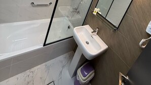 A modern bathroom with a glass-enclosed shower, a white sink, and a mirror with integrated lighting. - AL SHARQ HOTEL L L C (Sharjah)