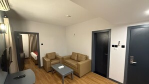 A modern hotel room with a sofa, a small table, a TV, and a door with a keypad lock. - AL SHARQ HOTEL L L C (Sharjah)