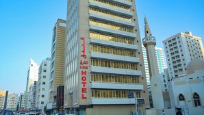 A tall hotel with multiple balconies and a minaret, surrounded by other buildings. - AL SHARQ HOTEL L L C (Sharjah)