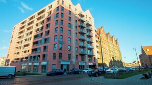 Un edificio de varios pisos con balcones, estacionamiento y cielo despejado.