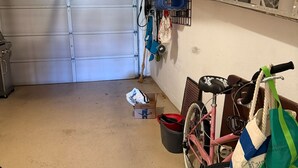 Un garage contenant un vélo, une poubelle et une boîte posée sur le sol.