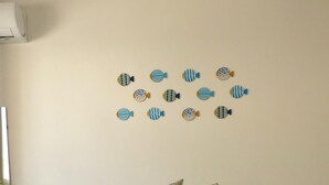 Une chambre à coucher avec un lit, des oreillers, un décor mural représentant des poissons et une lampe de chevet.
