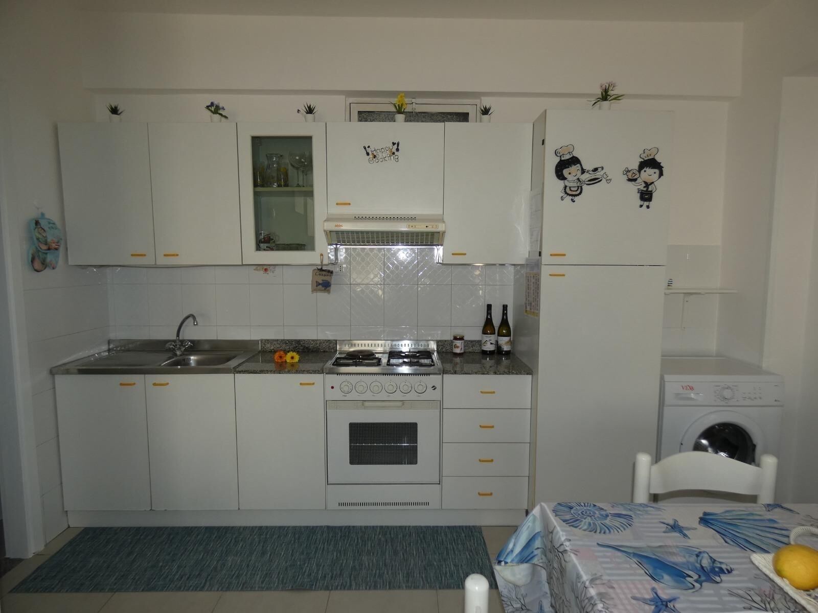 Una cuina funcional amb armaris blancs, fogó, rentatallopes i microones.
