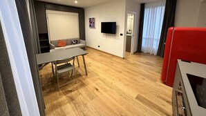 Ein modernes Wohnzimmer mit einer Couch, einem Tisch, einem Flachbildfernseher und einem roten Schrank.