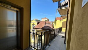 Ein Balkon mit Metallgeländer, einer Tür und Blick auf benachbarte Gebäude.